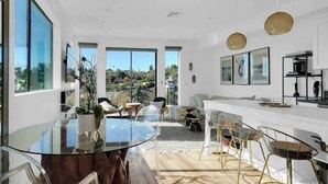 Un espacio habitable moderno y de concepto abierto, con mesa de comedor de vidrio, zona de estar y cocina.