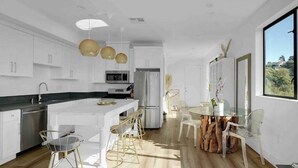 Una cocina moderna con armarios blancos, una isla central con taburetes altos e iluminación colgante.