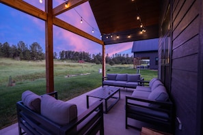 Une terrasse extérieure dotée d’une pergola en bois, d’un espace salon et de guirlandes lumineuses.