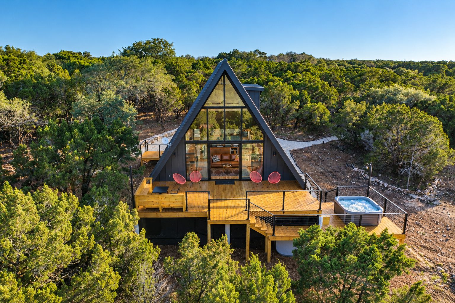 A modern house with a large glass window, wooden deck, and a hot tub.