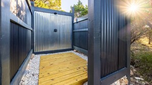 Un espace extérieur clos, doté d’une terrasse en bois et d’une porte en métal.