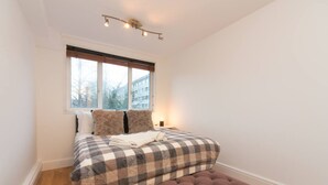 A bedroom with a bed, a window, and a wooden floor. - 10 min to Regent's Park · Bright Central 1-Bed - Pass the Keys (London)