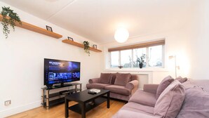 A living room with a flat-screen TV, a sofa, a coffee table, and a window with a view. - 10 min to Regent's Park · Bright Central 1-Bed - Pass the Keys (London)