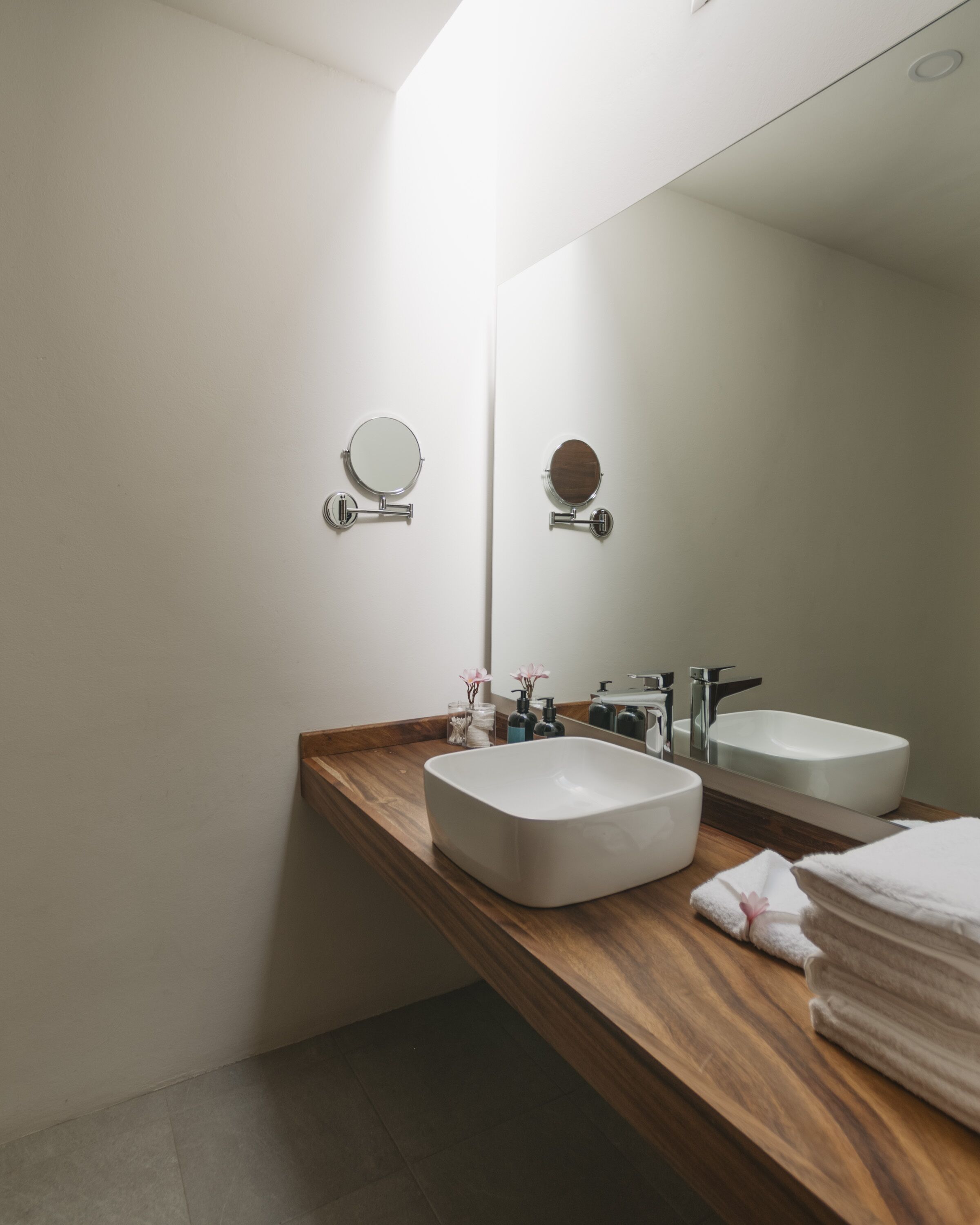 A modern bathroom with two sinks, a wooden vanity, and a large mirror.