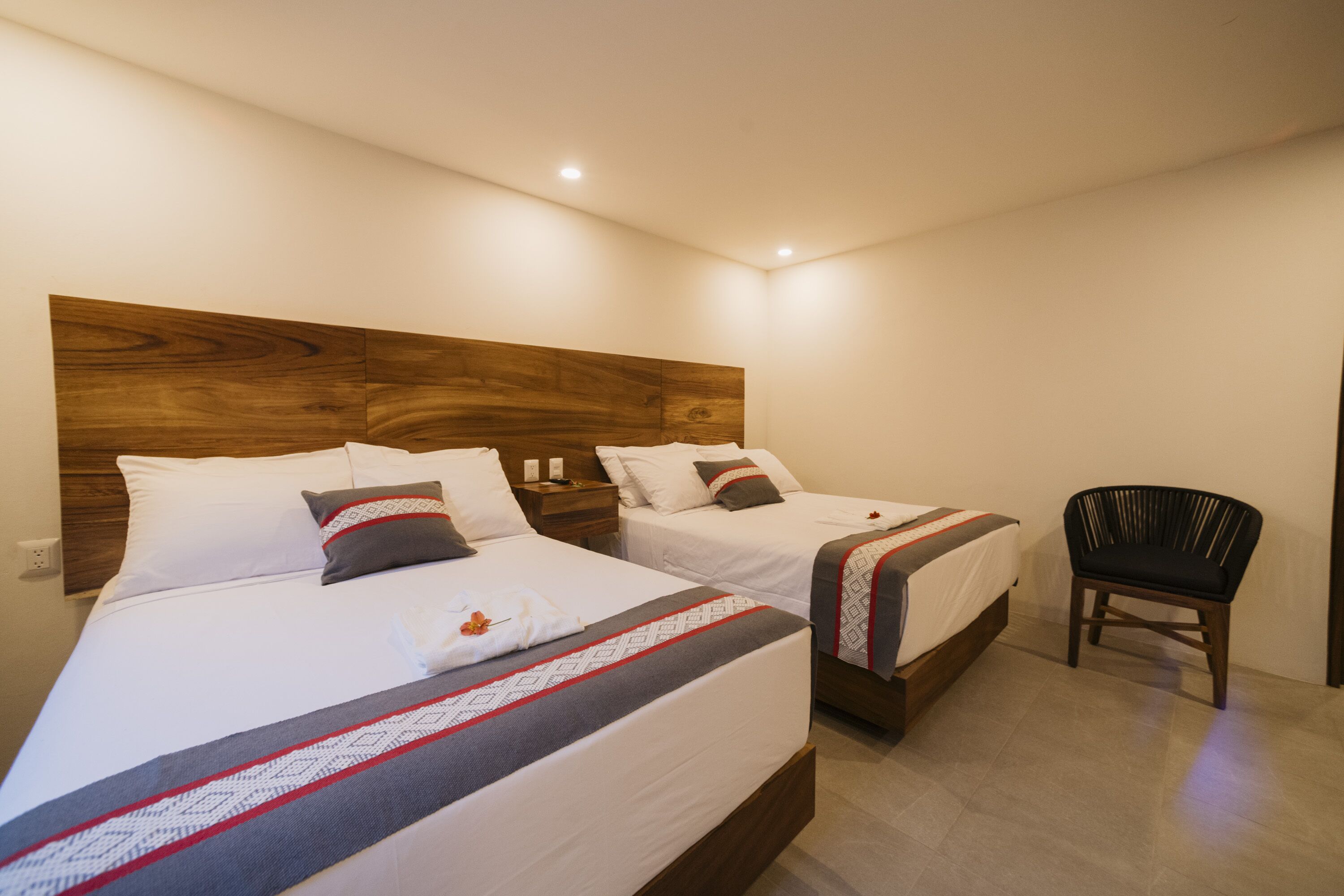 Ein Hotelzimmer mit zwei Betten, einem Holzkopfteil und einem Sessel.