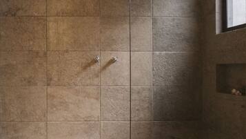 A shower area with stone tiles and a pebble-patterned floor.