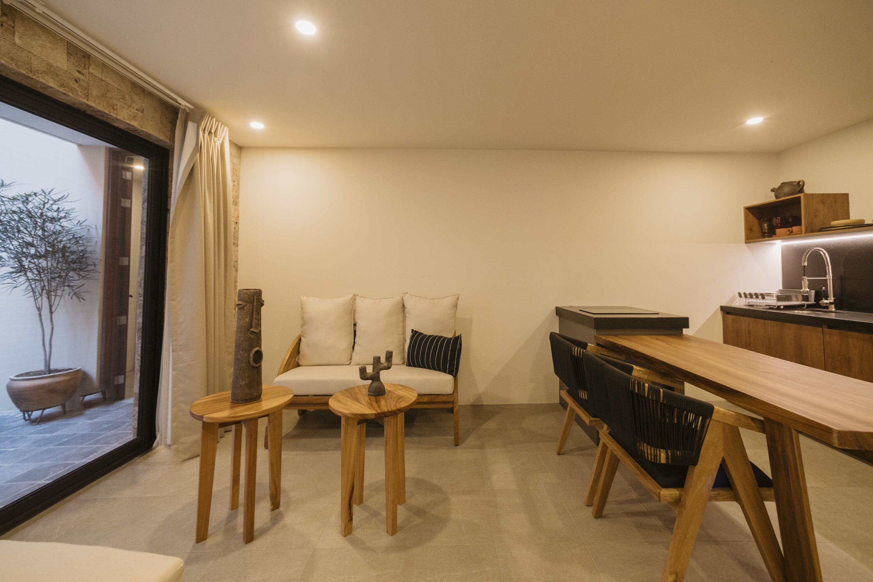 A modern living room with a sofa, two wooden side tables, and a dining table with chairs.