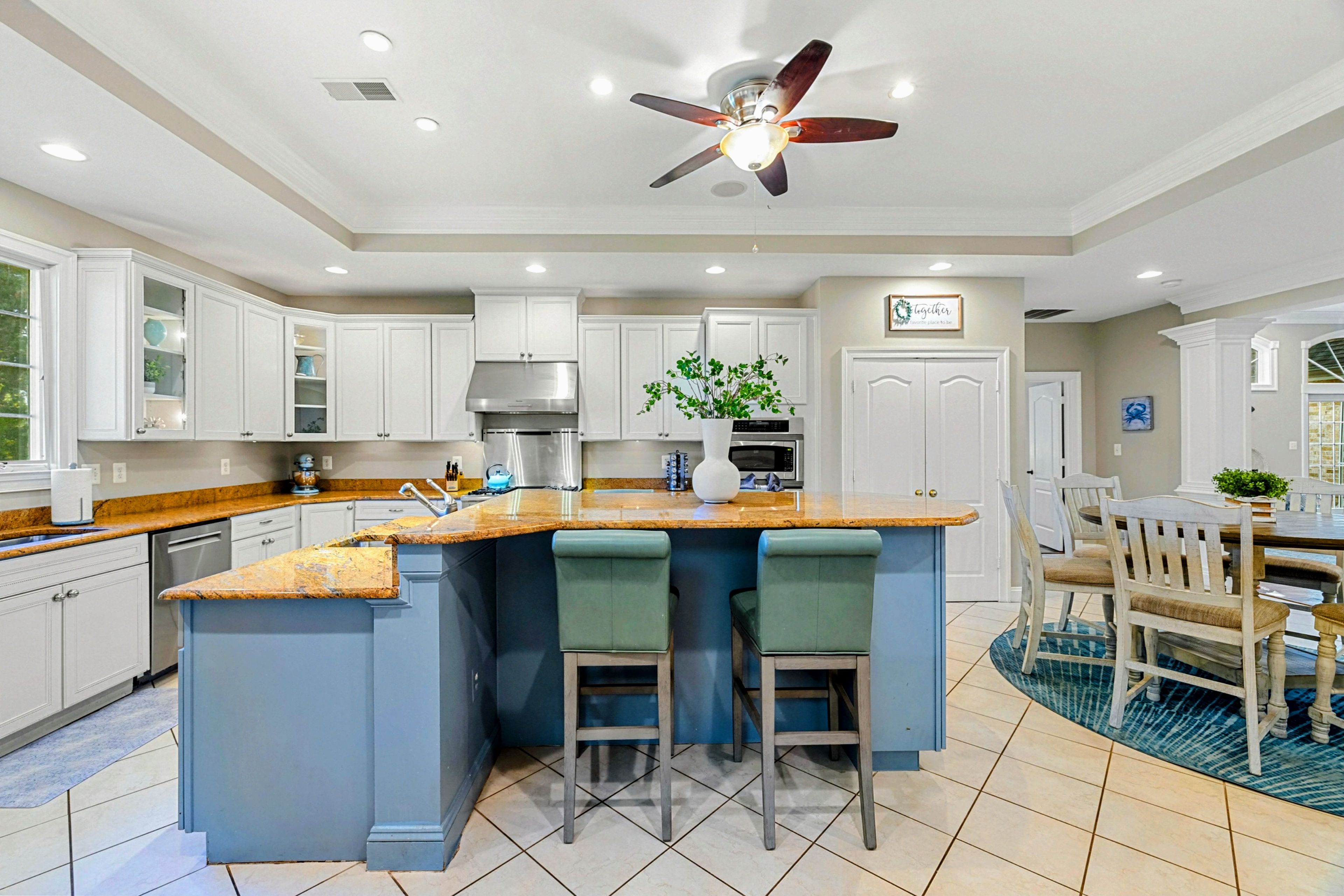Una cocina moderna con una isla central, taburetes de bar y un ventilador de techo.
