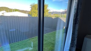 Une pièce avec une grande fenêtre, un radiateur et un rideau.