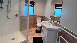 Une salle de bain moderne avec une douche à parois de verre, un lavabo blanc et des toilettes.
