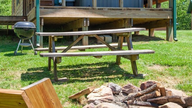 A wooden cabin with a porch, a hot tub, and a grill.