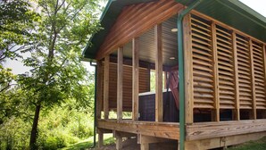 Una baita di legno con portico coperto e ampie finestre, immersa nel verde.