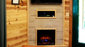 A cozy room with a fireplace, a mounted TV, and a wooden table.
