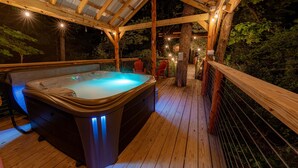 Un bain à remous sur une terrasse en bois, surmontée d’une pergola également en bois.