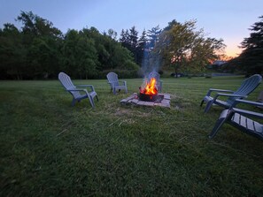 A fire pit with chairs around it in a grassy outdoor area. - Cayuga Creek Quarters (Cheektowaga)
