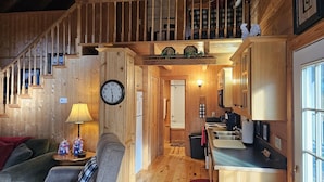 L’intérieur d’une cabane en bois comprend un escalier, un coin repas, une cuisine et une salle de bain.