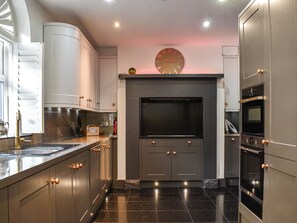Una cucina moderna con forno integrato, un orologio grande e una radio.
