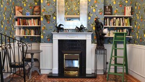 A room with a fireplace, bookshelves, a ladder, and a decorative statue.