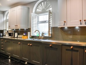 Una cocina moderna con una encimera larga, electrodomésticos integrados y una ventana con contraventanas.