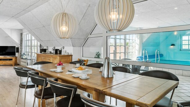 Un espace repas moderne avec une table en bois, des chaises noires et deux lampes suspendues.
