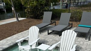 Une piscine à l’eau claire, entourée de chaises longues et d’une terrasse en pierre.
