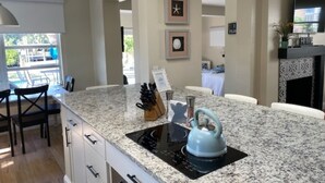 Une cuisine moderne dotée d’un plan de travail en granit, d’une bouilloire et d’une plaque de cuisson à induction noire.