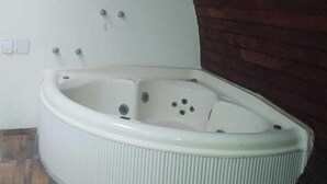 A corner bathroom with a freestanding bathtub, a white wall, and a wooden floor. - POUSADA VALE ENCANTADO MACAÉ (Macaé)