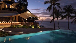 Un resort moderno con piscina, asientos al aire libre y vista al océano.
