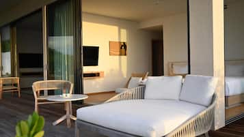 Una habitación de hotel moderna con una cama grande, un sofá, una mesita y un televisor.