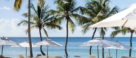 Una piscina al aire libre, sombrillas, sillones reclinables de piscina
