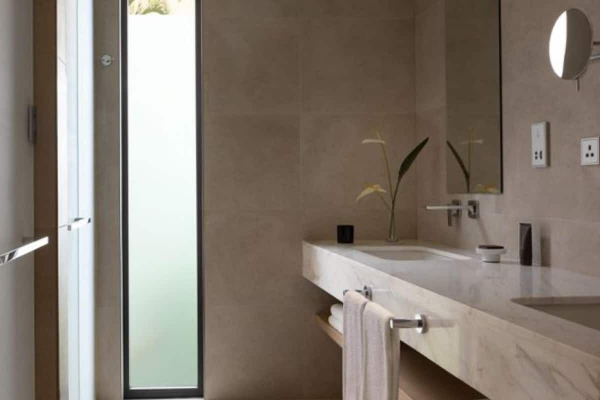 Un baño moderno con dos lavabos, un espejo grande y un perchero para toallas.