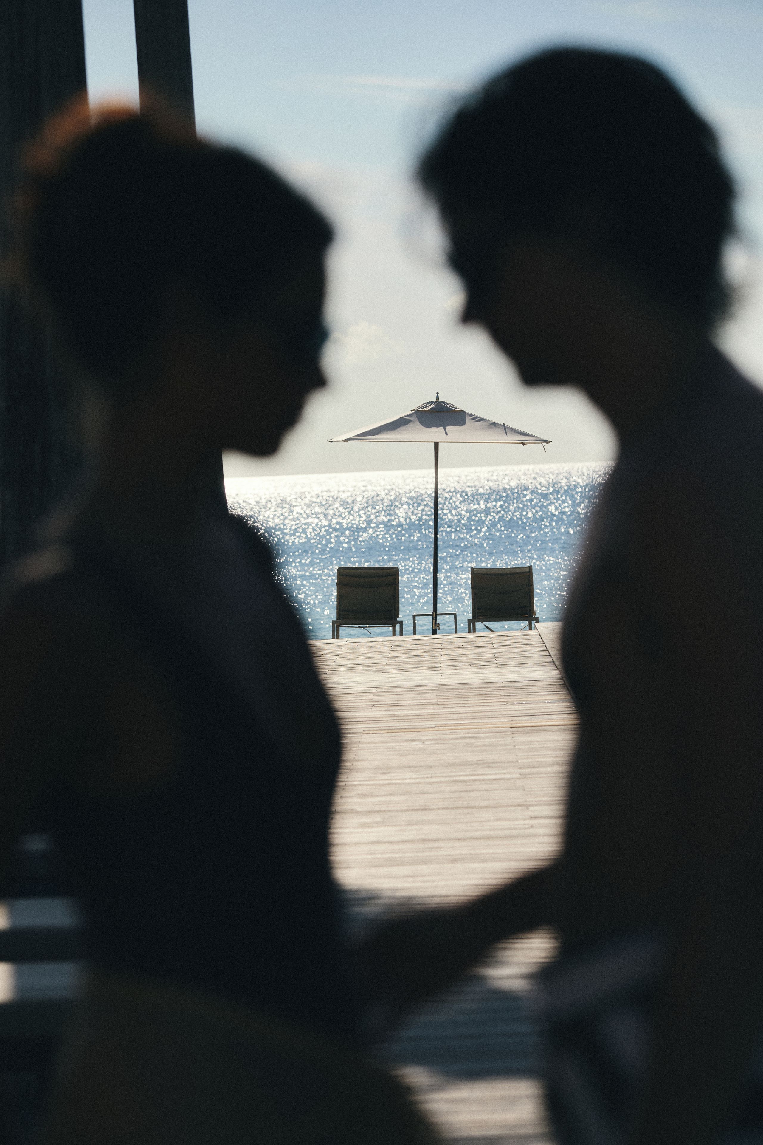 Due persone sedute a un tavolo con vista sulla spiaggia e un ombrellone.