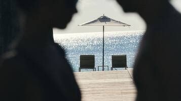 Due persone sedute a un tavolo con vista sulla spiaggia e un ombrellone.