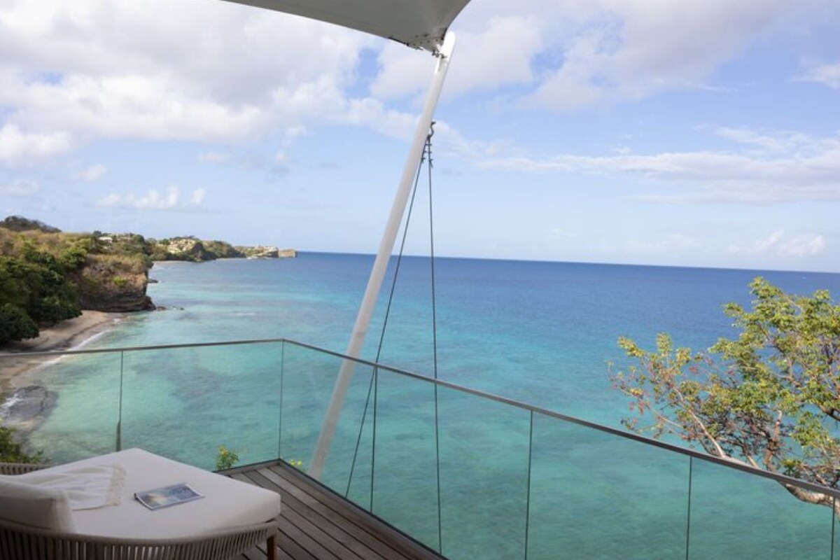 A balcony with a clear view of the ocean and a beach.