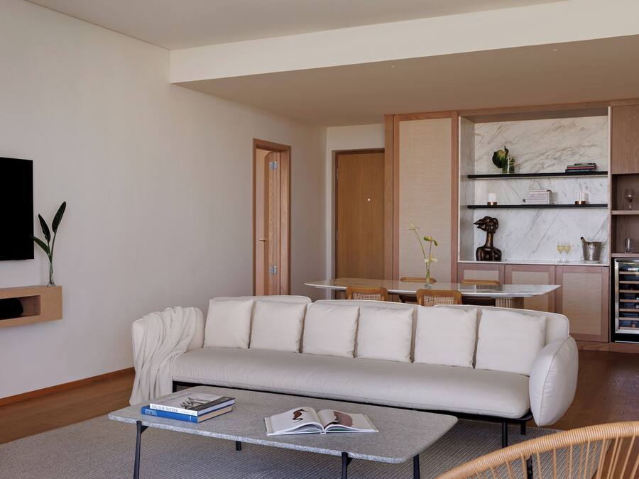 Una sala de estar moderna con un sofá, una mesa de centro y un televisor montado en la pared.
