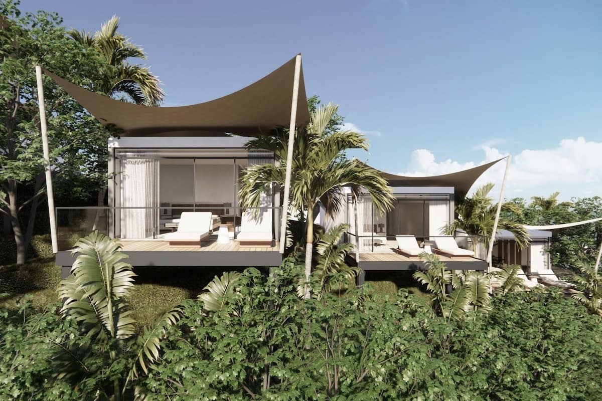 A modern house with a balcony, large windows, and a tropical garden.