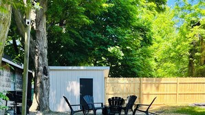 A backyard with a gravel pathway leading to a shed, surrounded by greenery and a wooden fence. - Cozy Colonial in Downtown Westfield, NY (Westfield)