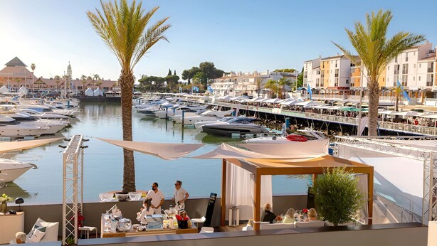 A marina with boats docked, a covered seating area, and a view of the surrounding buildings. - Vilamoura Marina Villa  (Loulé)
