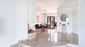 A modern interior with a dining area, a curved staircase, and a marble floor. - Vilamoura Marina Villa  (Loulé)