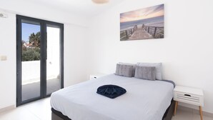 A bedroom with a bed, a painting, a nightstand, and a sliding glass door leading to an outdoor area. - Vilamoura Marina Villa  (Loulé)