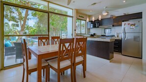 A modern kitchen with a dining area, large windows, and a view of the outdoors. - Tranquilidad 3 Bedroom Home At El Cielo (Playa del Carmen)
