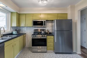 Una cocina compacta equipada con estufa a gas, horno, microondas y refrigerador de acero inoxidable.