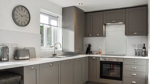 Una cocina moderna con gabinetes grises, un lavamanos de acero inoxidable y un horno empotrado.