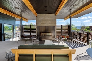 An outdoor seating area with a stone fireplace, wooden beams, and a view of the mountains. - Gravity Haus Missoula (Missoula)