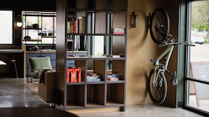 Ein Zimmer mit Bücherregal, einem grünen Sessel, einem an der Wand befestigten Fahrrad und Blick auf die Straße.