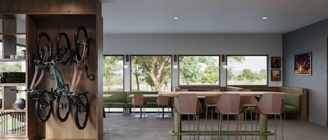 Un interior modern amb un suport de bicicleta de fusta, seients verds i grans finestres que ofereixen vista a arbres i muntanyes.