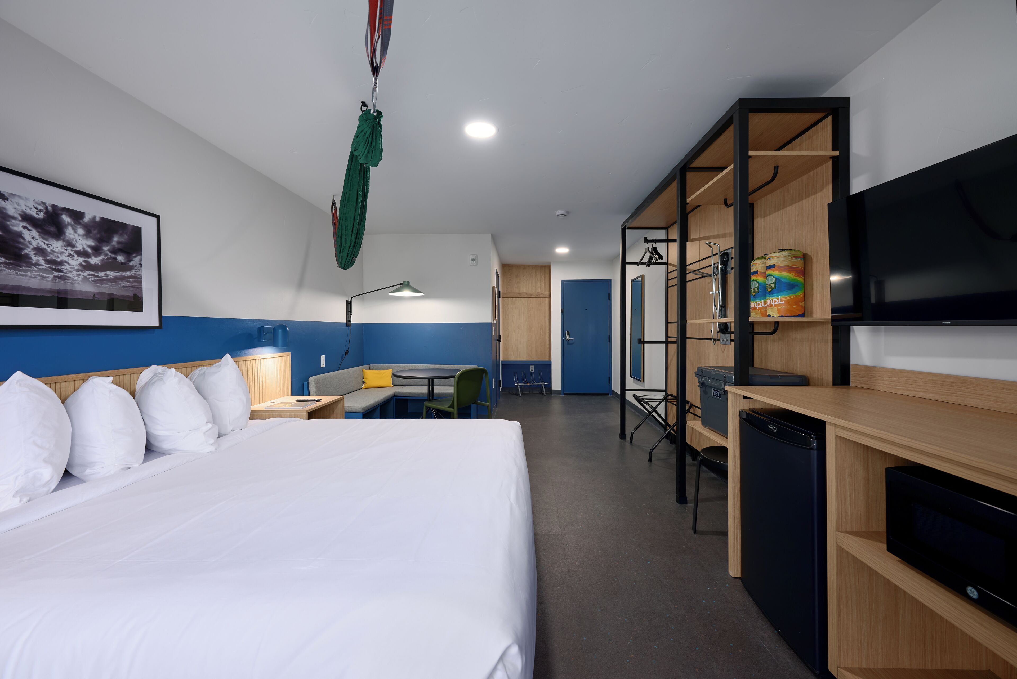 Een hotelkamer met een bed, een bureau, een stoel, een televisie en een kledingkast.