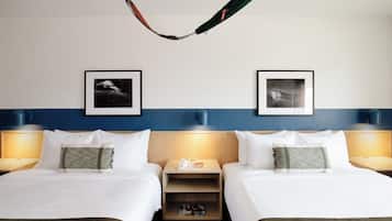 Ein Hotelzimmer mit zwei Betten, einer Hängematte, gerahmten Bildern an der Wand und Nachttischlampen.