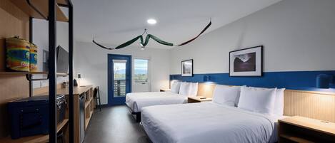 Ein Hotelzimmer mit zwei Betten, einem Schreibtisch, einem Stuhl, einem Kleiderschrank und Blick ins Freie.