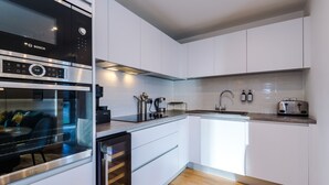 A modern kitchen with white cabinetry, a Bosch microwave, a built-in dishwasher, and a stainless steel toaster. - Sleek Apartment near the City Center (Birmingham)